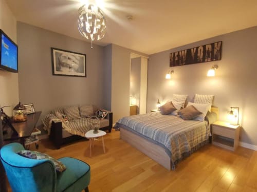 Deluxe apartment at Hôtel OH Sèvres with queen bed, seating area, wooden floors, and modern lighting in Sèvres, France