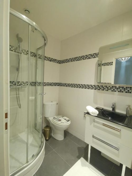 Modern bathroom in Deluxe Apartment at Hôtel OH Sèvres Autrement with shower, toilet, sink and mosaic tile accents