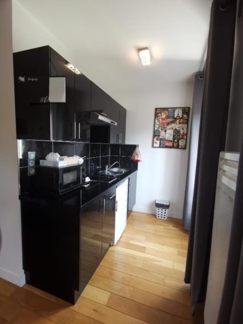 Modern black kitchen in Deluxe Apartment at Hôtel OH Sèvres Autrement, Sèvres with glossy cabinetry and wooden flooring