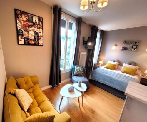 Deluxe apartment at Hôtel OH Sèvres with yellow sofa, queen bed, and modern décor in Sèvres
