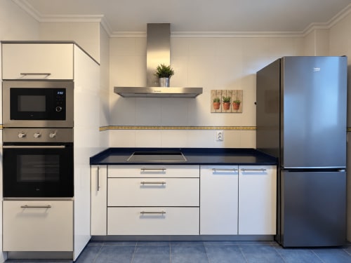 Cocina moderna del apartamento A Dourada en Holibai, Baiona con electrodomésticos de acero inoxidable y encimeras oscuras
