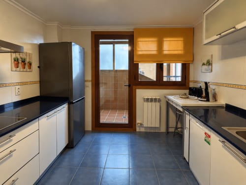 Cocina moderna en apartamento A Dourada de Holibai, Baiona con electrodomésticos de acero inoxidable, encimeras negras y vistas al mar