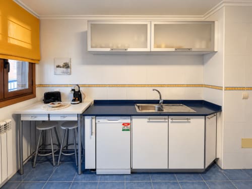 Cocina moderna en apartamento A Dourada del hotel Holibai, Baiona, con lavavajillas, fregadero y barra de desayuno