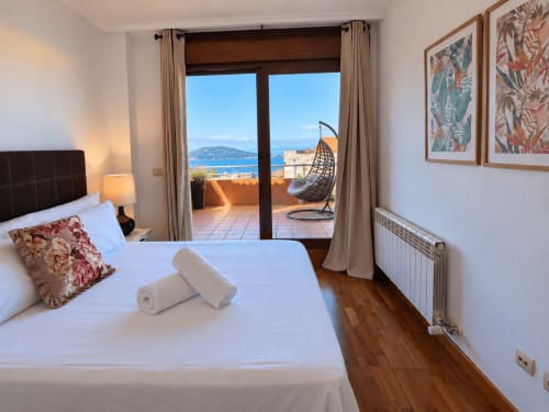 Dormitorio moderno en apartamento Holibai Baiona con terraza vista al mar, cama doble y paisaje costero