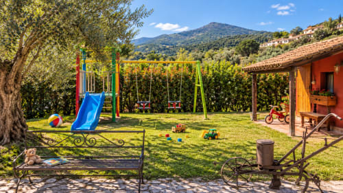 Colorido parque infantil con columpios, tobogán y juguetes en el soleado jardín de la villa El Descanso del Peregrino en Guadalupe