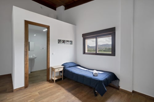 Dormitorio luminoso en la casita Holiday Dreams Ronda con cama individual, mesita de madera, vistas a las montañas y baño en suite