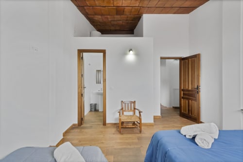 Dormitorio luminoso en la casita Holiday Dreams Ronda con techo de madera, dos camas, silla rústica y acceso al baño