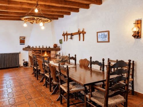Comedor rústico en El Descanso del Peregrino de Guadalupe con vigas de madera, chimenea y estilo español tradicional