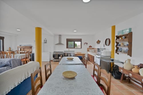 Amplia cocina abierta y comedor en la casita Laguna Espejo de Holiday Dreams Ronda, con muebles de madera y detalles en amarillo