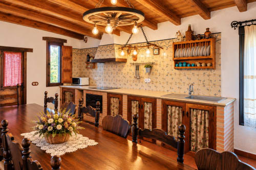Cocina rústica de la villa El Descanso del Peregrino con vigas de madera, papel pintado floral y decoración tradicional