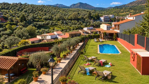 Villa El Descanso del Peregrino con vistas a la montaña, piscina, jardín verde y construcciones de terracota en Guadalupe, Cáceres