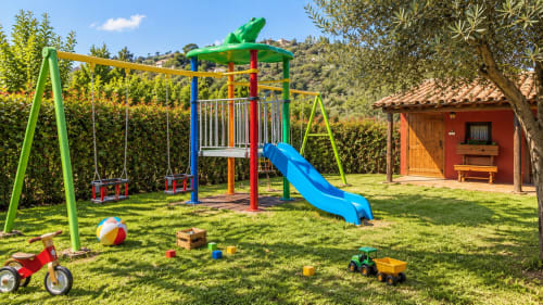 Colorido parque infantil con tobogán y columpios en la villa El Descanso del Peregrino en Guadalupe, Cáceres