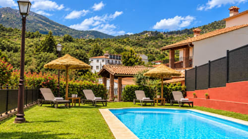 Villa de lujo con piscina, vistas a la montaña, tumbonas y arquitectura española tradicional en Guadalupe, Cáceres