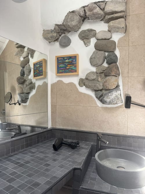 Modern bathroom with stone wall art installation and colorful fish painting in Sormano apartment