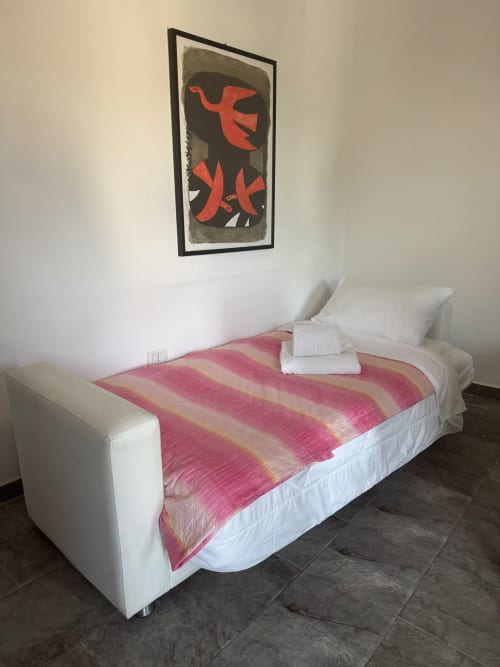 Modern bedroom at THE V Collection Sormano with white bed, pink striped blanket, and abstract red artwork on wall