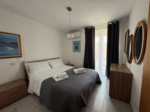 Modern bedroom at THE V Collection apartment in Sormano with double bed, black accents, balcony access, and mountain views