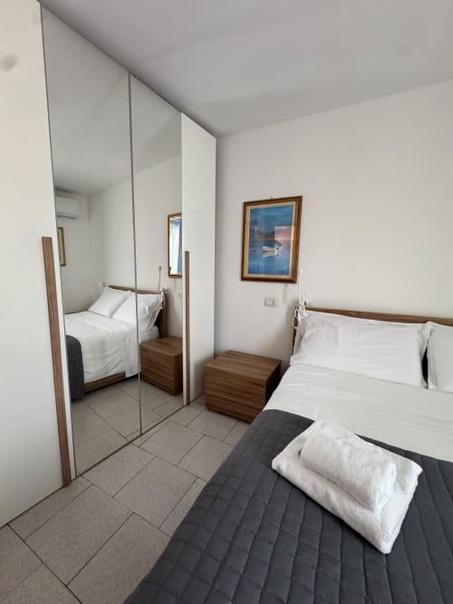 Modern bedroom at THE V Collection in Sormano with mirrored wardrobe, white bedding, and mountain view artwork