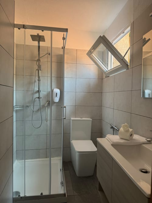 Modern bathroom at THE V Collection, Sormano with glass shower, white toilet, sink, and skylight window