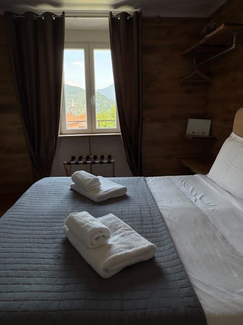 Camera da letto con vista montagna e asciugamani bianchi arrotolati sul letto presso THE V Collection a Sormano