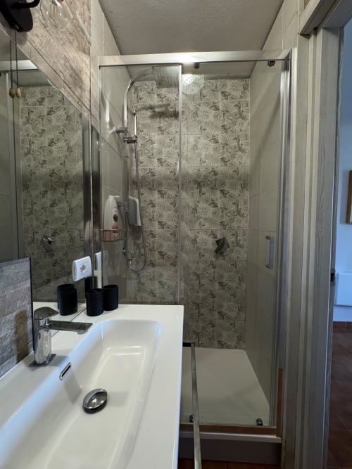 Bagno moderno con doccia walk-in, lavandino bianco e pareti rivestite di piastrelle decorate nell'appartamento THE V Collection a Sormano, Italia