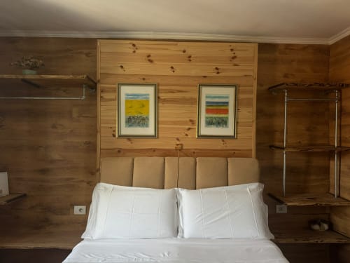 Camera da letto accogliente in legno presso THE V Collection a Sormano con biancheria bianca, testata marrone e quadri paesaggistici