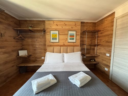 Spazioso dormitorio in legno presso THE V Collection, Sormano con letto matrimoniale, biancheria bianca, asciugamani e vista sulle montagne