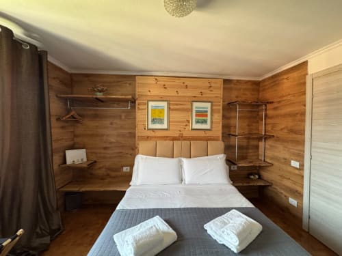 Camera da letto in legno accogliente a THE V Collection, Sormano con letto matrimoniale, cuscini bianchi, vista montagna e comfort moderni