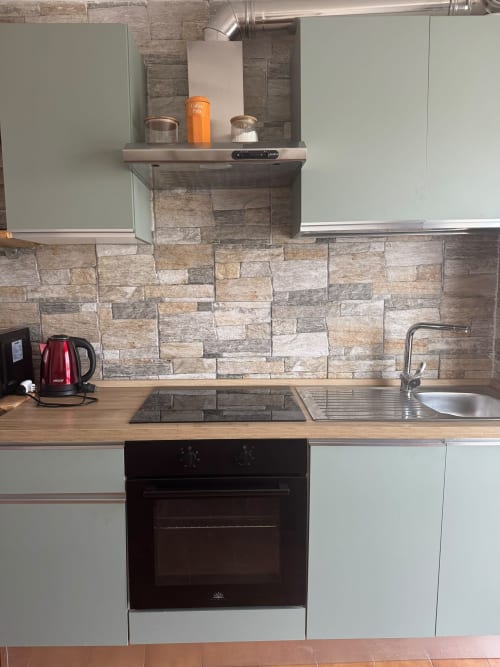 Cucina moderna dell'appartamento a Sormano con rivestimento in pietra, banconi in legno e elettrodomestici in acciaio inossidabile