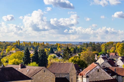 Vue aérienne du townscape d'Esches avec toitures historiques, arbres d'automne et ciel bleu nuageux