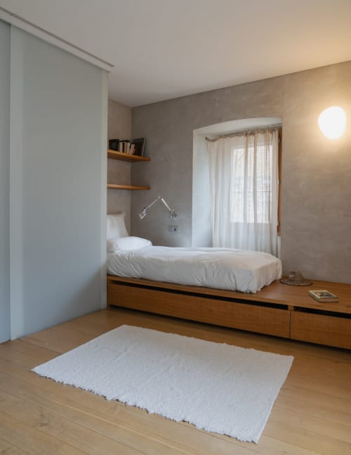 Modern bedroom at Alemanys 5 B&B in Spain with wooden bed platform, white linens, and minimalist design