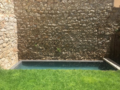 Modern pool with turquoise water, manicured lawn, and rustic stone walls at Alemanys 5 boutique hotel in Spain