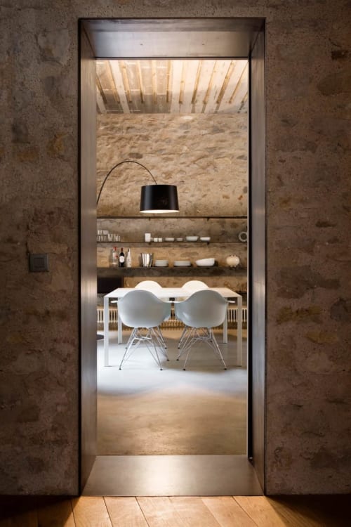 Modern dining room at Alemanys 5 BnB through open doorway with white chairs and arc lamp