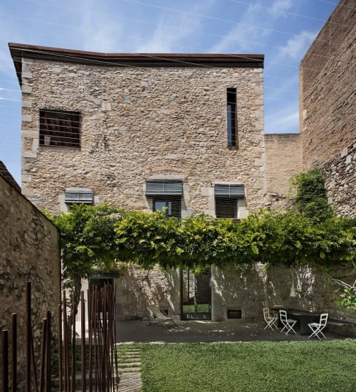 Alemanys 5 B&B courtyard with stone building, greenery, and seating area in Spain