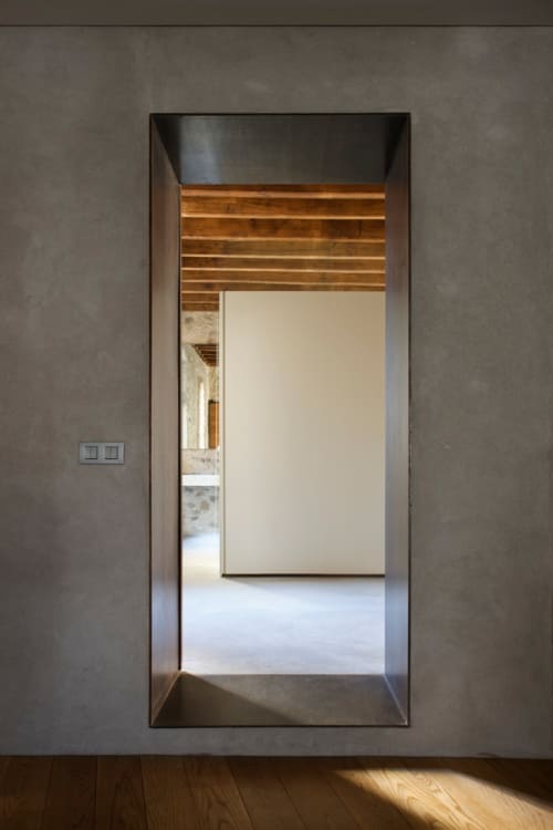 Modern doorway at Alemanys 5 boutique hotel in Spain, featuring concrete walls and wooden ceiling beams