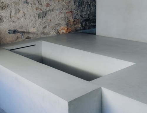 Modern minimalist concrete sink at Alemanys 5 B&B in Spain with recessed basin and exposed stone wall backdrop