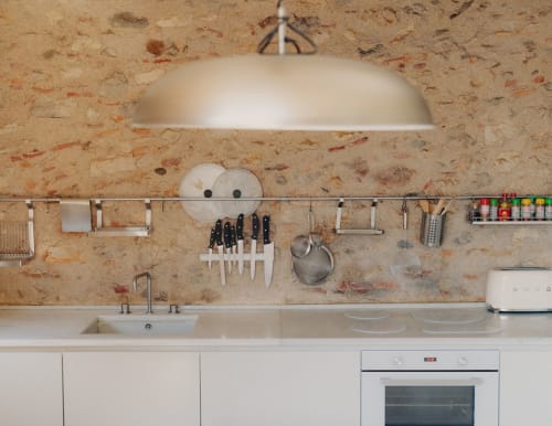 Modern kitchen at Alemanys 5 B&B in Spain with cork backsplash, open shelving, and stainless steel cookware