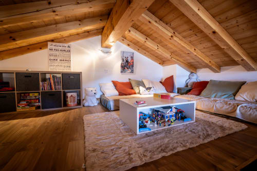 Salon douillet en mezzanine aux Chalets d'Aline à La Plagne avec poutres apparentes, canapés et espace jeux