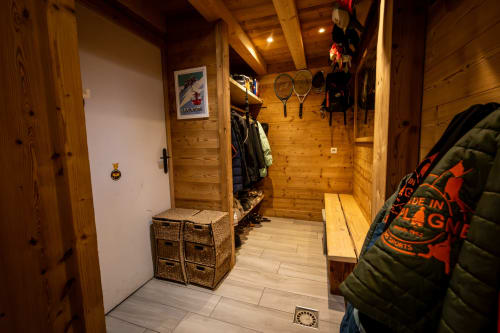 Entrée du chalet en bois des Chalets d'Aline à La Plagne avec rangements pour équipements de ski, vêtements et matériel sportif