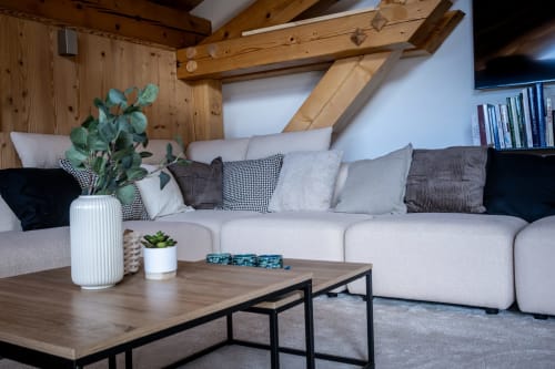 Salon alpin moderne aux Chalets d'Aline : canapé crème, poutres bois et vue montagne à La Plagne