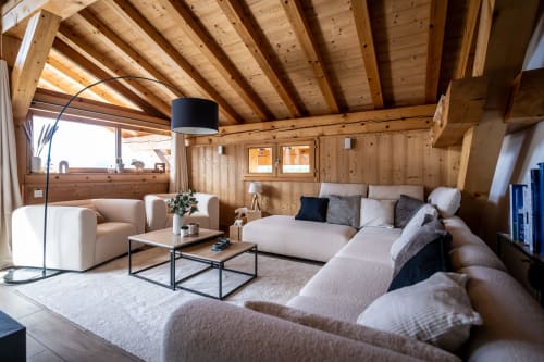 Spacieux salon mansardé aux Chalets d'Aline B&B à La Plagne avec poutres apparentes, mobilier confortable et moderne