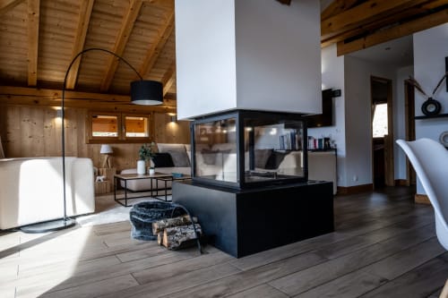 Spacieux séjour ouvert aux Chalets d'Aline à La Plagne avec cheminée, lampadaire arc et poutres en bois