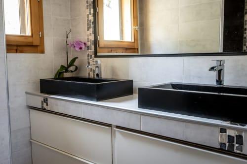 Salle de bain moderne aux Chalets d'Aline, La Plagne Tarentaise : double vasque noire, meuble blanc et orchidée.