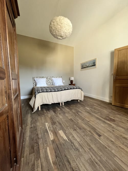 Chambre spacieuse du gîte 1694 avec lit queen-size, parquet, suspension et portes rustiques en bois à Scorbe