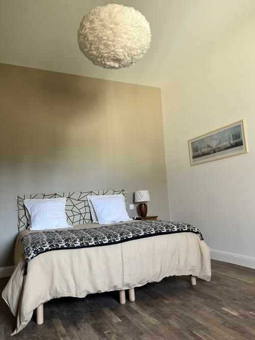 Chambre moderne du gîte 1694 à Scorbe Clairvaux avec lampe suspendue blanche et tête de lit géométrique