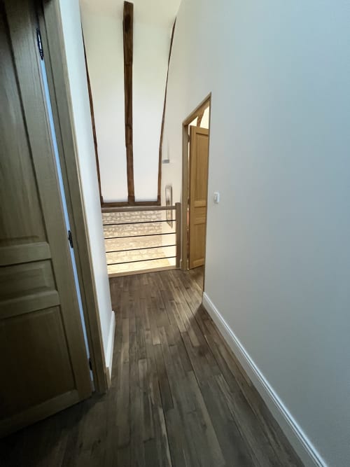 Couloir avec parquet et murs blancs menant à la chambre, gîte 1694, Scorbe Clairvaux