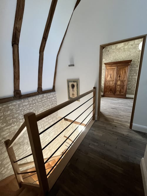 Chambre moderne du gîte 1694 à Scorbe Clairvaux avec poutres apparentes, lit à structure métallique et accès à la pièce voisine