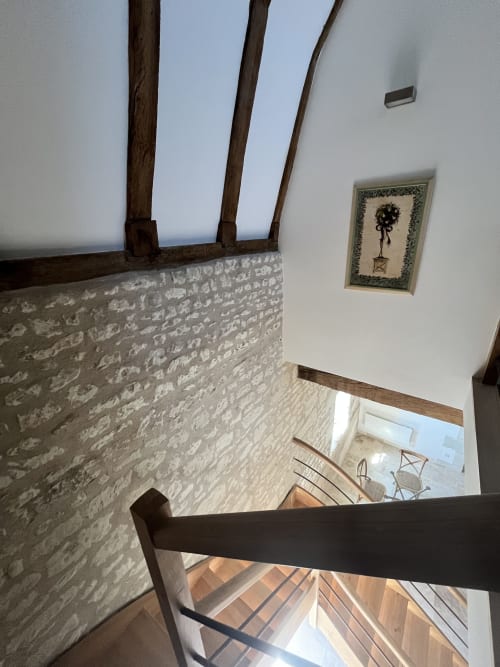 Escalier aux murs en pierre apparente et poutres en bois du Gîte 1694, location de maison de campagne française