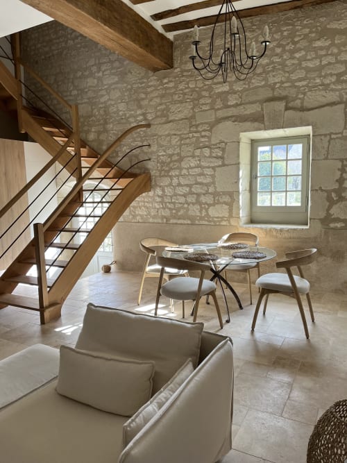 Salle à manger rustique avec murs en pierre, escalier hélicoïdal en bois et mobilier contemporain au Gîte 1694