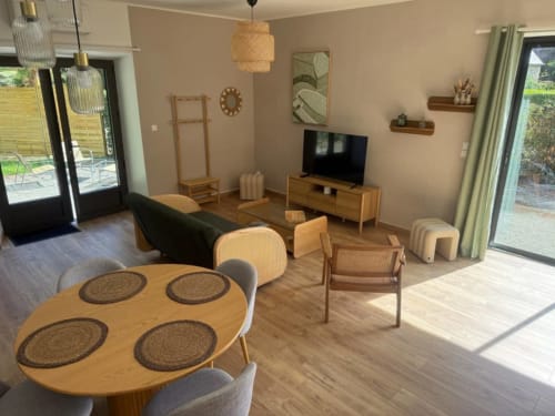 Séjour contemporain au Clos de l'Arguenon avec table à manger, coin salon, TV et accès au jardin à Val-d'Arguenon