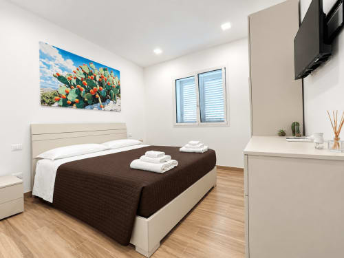 Modern bedroom at Villa Eraklea Noto with queen bed, cactus artwork, wooden floors, and contemporary furnishings